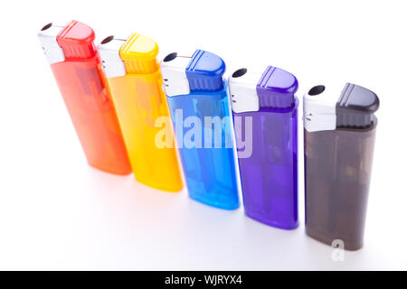 Row of vividly coloured plastic disposable lighters for smokers in red, yellow, two shades of blue and black isolated on a white background Stock Photo