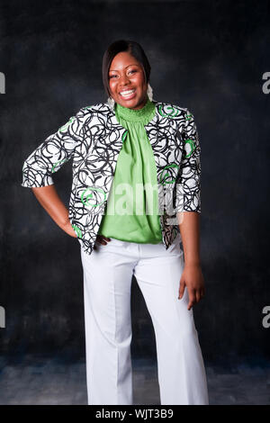 Beautiful African American business woman in white pants and green shirt with blazer standing and laughing with huge smile showing teeth Stock Photo