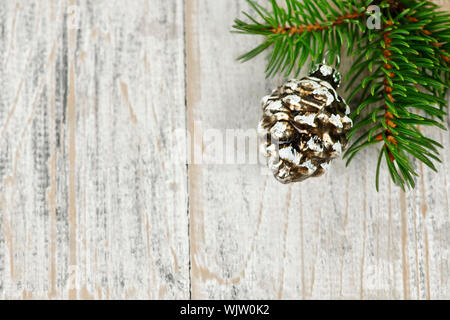 Golden Christmas pine cone on tree branch with wooden background Stock Photo