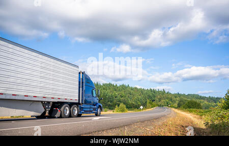 Big rig powerful professional industrial blue bonnet semi truck for long haul delivery commercial cargo going with refrigerator semi trailer on the su Stock Photo