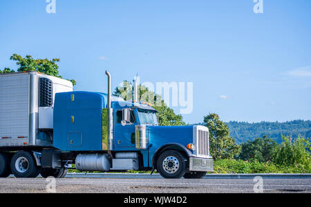 Big rig powerful professional industrial blue bonnet semi truck for long haul delivery commercial cargo going with refrigerator semi trailer on the su Stock Photo