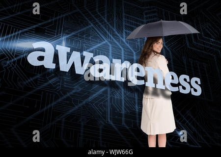 Businesswoman holding umbrella behind the word awareness against circuit board Stock Photo