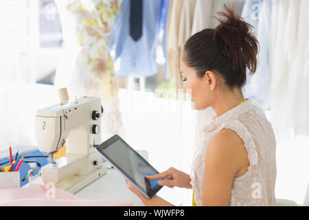 Side view of a young female fashion designer using digital tablet in the studio Stock Photo