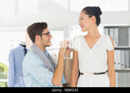 Male fashion designer adjusting dress on model in the studio Stock Photo