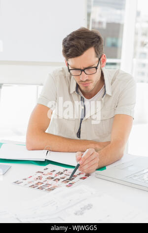 Concentrate male artist sitting at desk with photos in the office Stock Photo