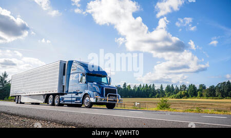 Big rig powerful professional industrial blue bonnet semi truck for long haul delivery commercial cargo going with refrigerator semi trailer on the su Stock Photo