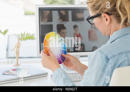 Blonde focused designer working at her desk holding a colour wheel in creative office Stock Photo
