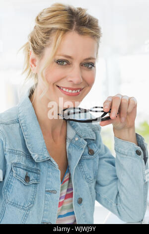 Blonde pretty designer looking at the camera with a smile in creative office Stock Photo