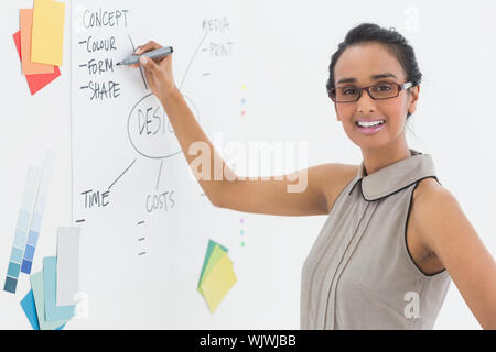 Designer writing on whiteboard and smiling at camera in creative office Stock Photo