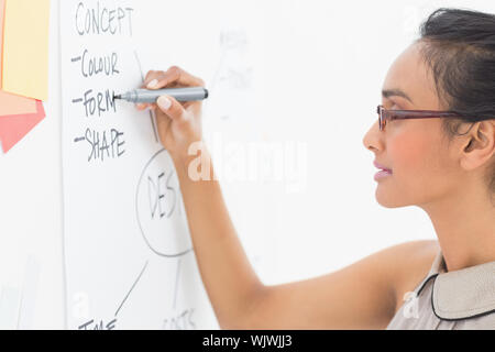 Designer writing on whiteboard in creative office Stock Photo