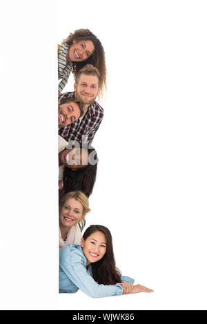 Happy group of young friends peeking from behind a wall on white background Stock Photo