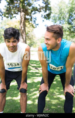 Smiling male marathon runners talking in park Stock Photo