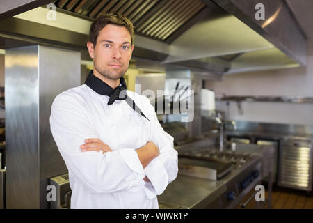 Portrait of a serious male cook with arms crossed standing in the kitchen Stock Photo