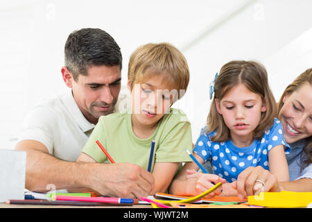 Parents assisting children in coloring at home Stock Photo