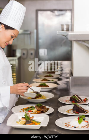 Side view of a female chef garnishing food in the kitchen Stock Photo