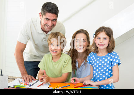 Portrait of smiling children and parents coloring at home Stock Photo