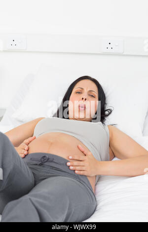 Portrait of pregnant woman suffering from labor pains lying in bed at hospital Stock Photo
