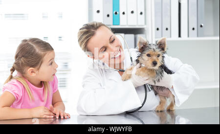 Female veterinarian examining puppy with girl in clinic Stock Photo