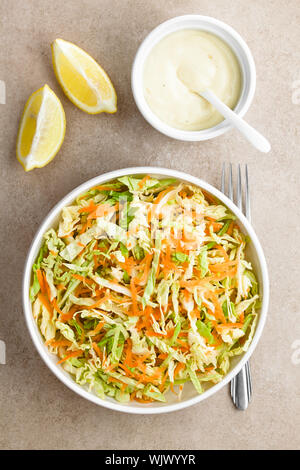 Coleslaw made of freshly shredded white cabbage and grated carrot with homemade mayonnaise-based salad dressing and lemon wedges on the side Stock Photo