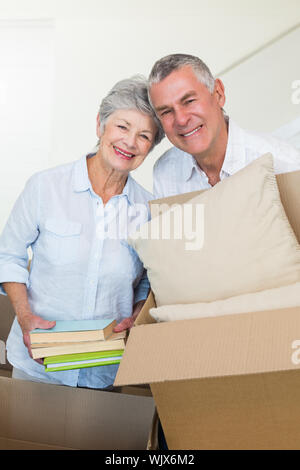 Happy senior couple moving into new home smiling at camera Stock Photo