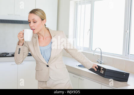 Businesswoman rushing out the door to work in the morning at home in the kitchen Stock Photo