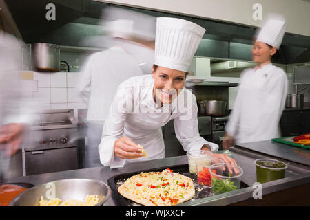 Happy chef preparing a pizza in a commercial kitchen Stock Photo