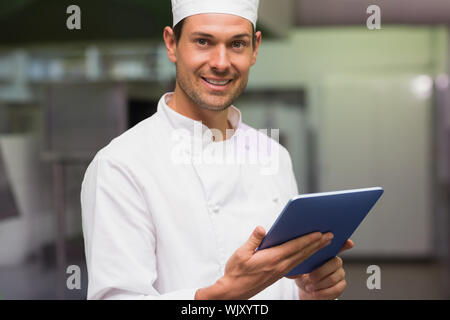 Happy chef using tablet pc in a commercial kitchen Stock Photo