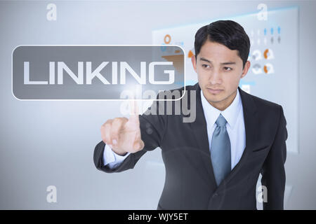 The word linking and unsmiling asian businessman pointing against technology interface Stock Photo