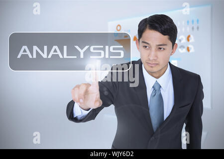 The word analysis and unsmiling asian businessman pointing against technology interface Stock Photo