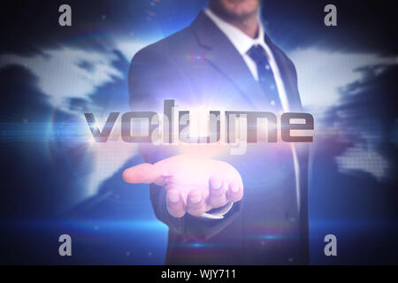 The word volume and businessman presenting against glowing world map on black background Stock Photo