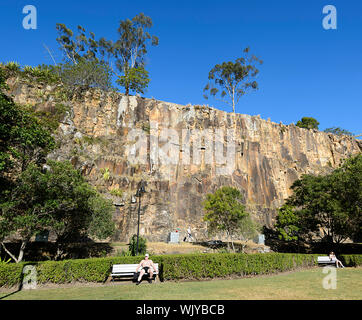 Two persons sunbathing on a bench in a park at Kangaroo Point Cliffs, Brisbane, Queensland, QLD, Australia Stock Photo