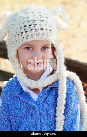 Beautiful little girl in a white bobble hat smiling at the camera. Shallow DOF. Stock Photo