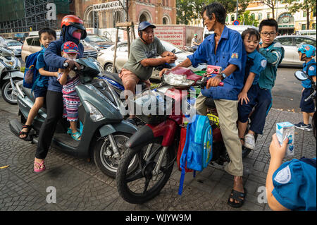 Parents on their motor scooters picking up their kids from school, Ho Chi Minh City, Vietnam Stock Photo