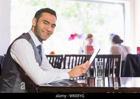 Happy businessman using tablet and smiling at camera Stock Photo
