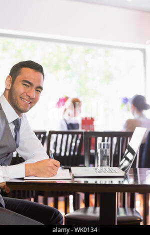 Happy businessman writing while smiling at camera Stock Photo
