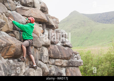 Focused man climbing a large rock face