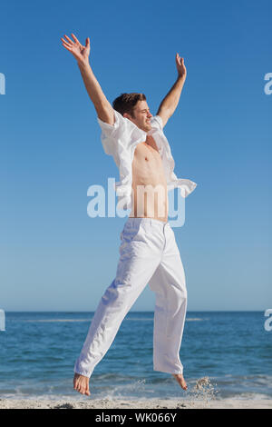 Attractive man jumping on beach Stock Photo