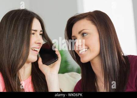 Two happy girls calling someone with a mobile phone Stock Photo