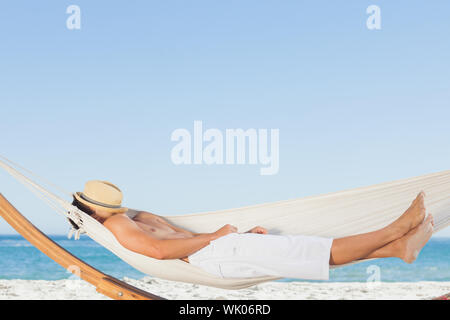 Man wearing straw hat relaxing in a hammock Stock Photo