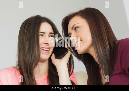 Two cheerful girls calling someone with a mobile phone Stock Photo