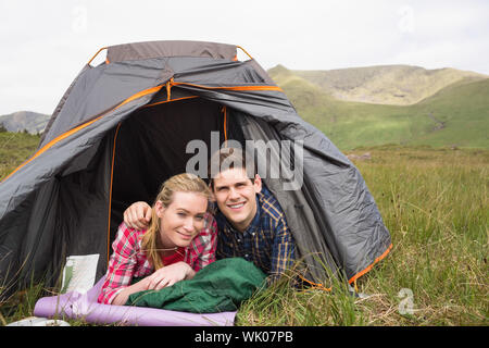 Happy couple lying in their tent and looking at camera Stock Photo
