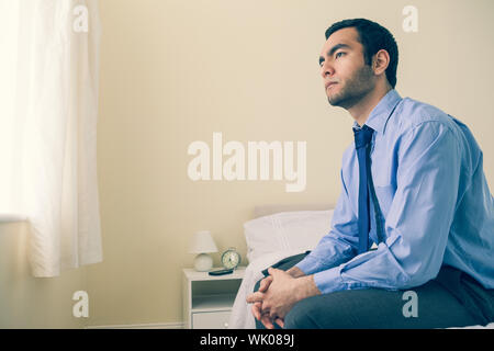 Thinking man looking away sitting on his bed Stock Photo