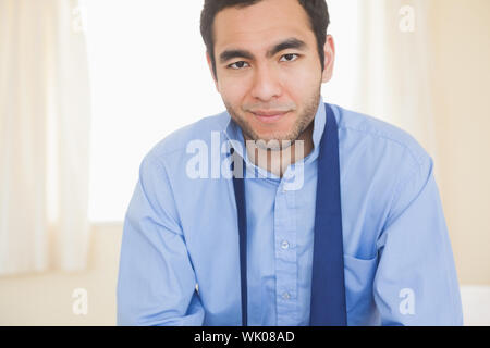 Relaxed man smiling at camera sitting on a bed Stock Photo