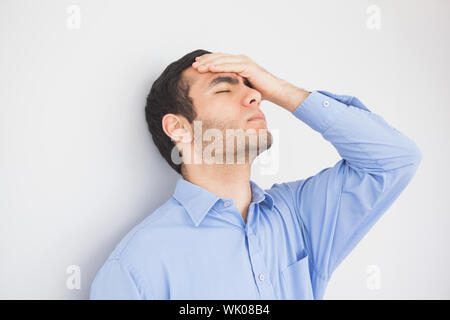 Irritated man with hand on forehead leaning against a wall Stock Photo