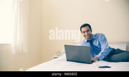 Content man lying on bed using a laptop Stock Photo