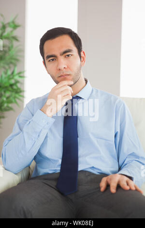 Young classy businessman thinking on cosy sofa Stock Photo