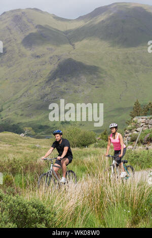Athletic couple biking through wilderness Stock Photo