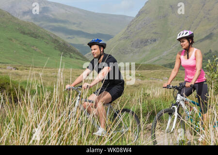 Athletic couple biking through countryside Stock Photo