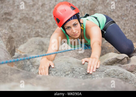 Determined girl climbing rock face Stock Photo