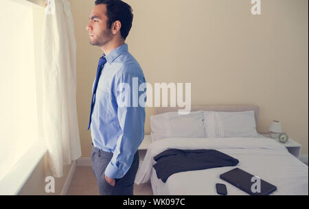 Frowning man standing looking out the window Stock Photo